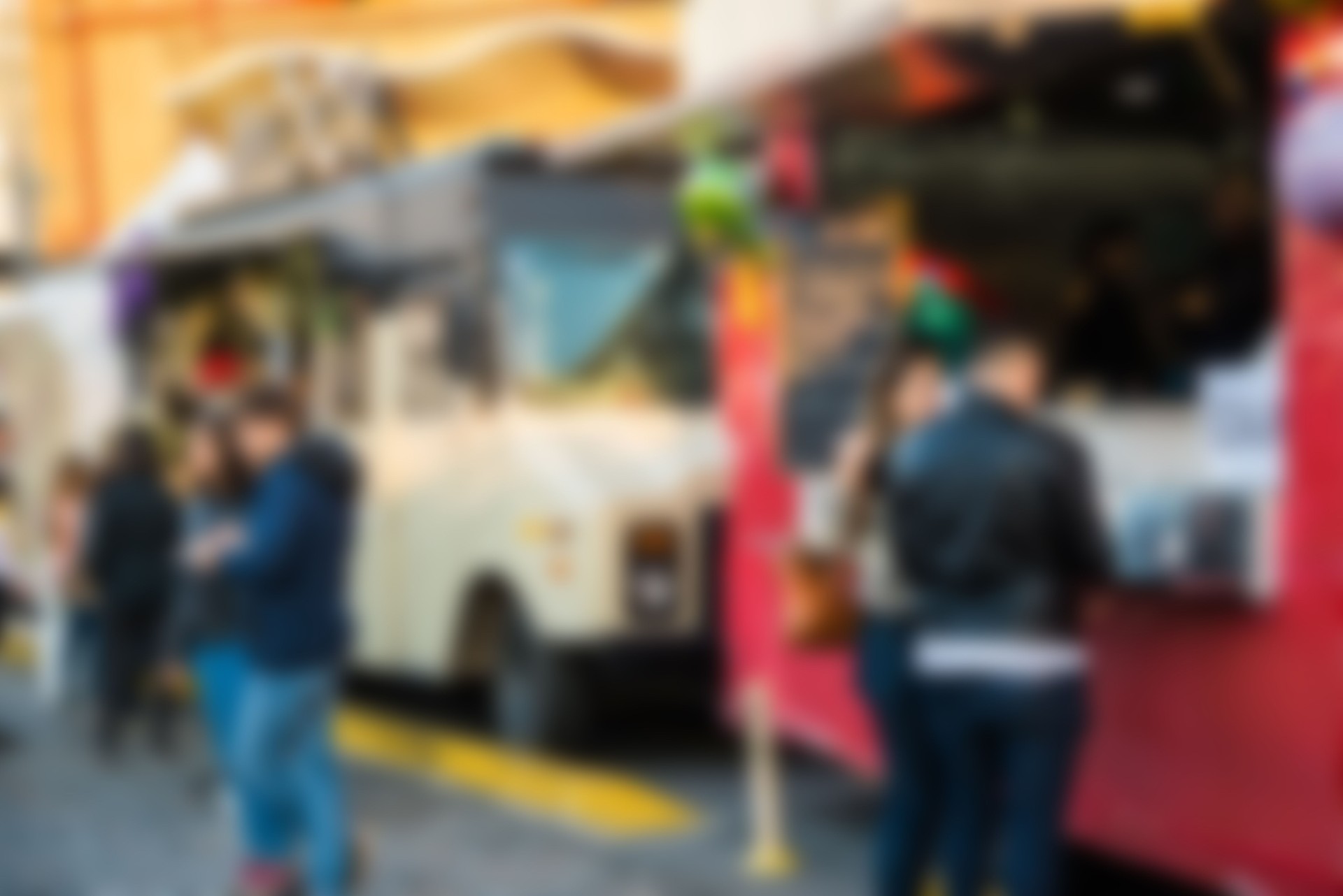 Food trucks and people at a street food market festival, blurred on purpose